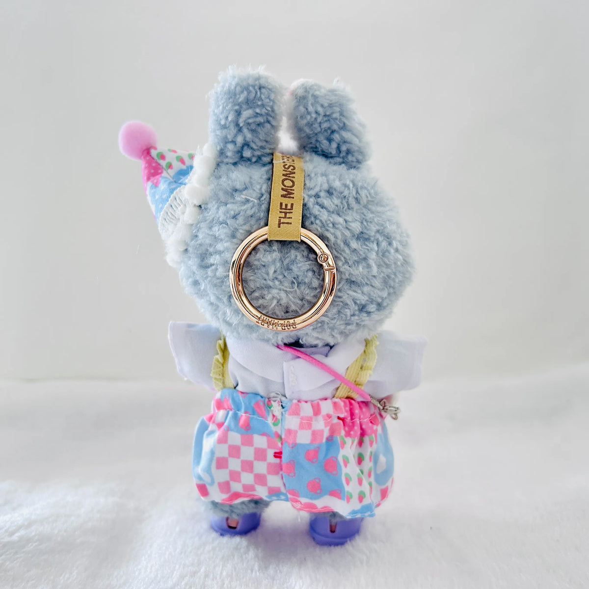 A back view Labubu wearing a clothing set of blue checkered overall dress and party cone hat
