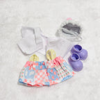 A doll outfit set back view, including a white top, a pink and blue patterned skirt, a hat and a pair of purple booties.