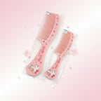 Two pink Hello Kitty hair combs in clear plastic packaging, displayed on a two-toned gray and white surface.