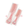Two pink Hello Kitty hair combs in clear plastic packaging, displayed on a two-toned gray and white surface.