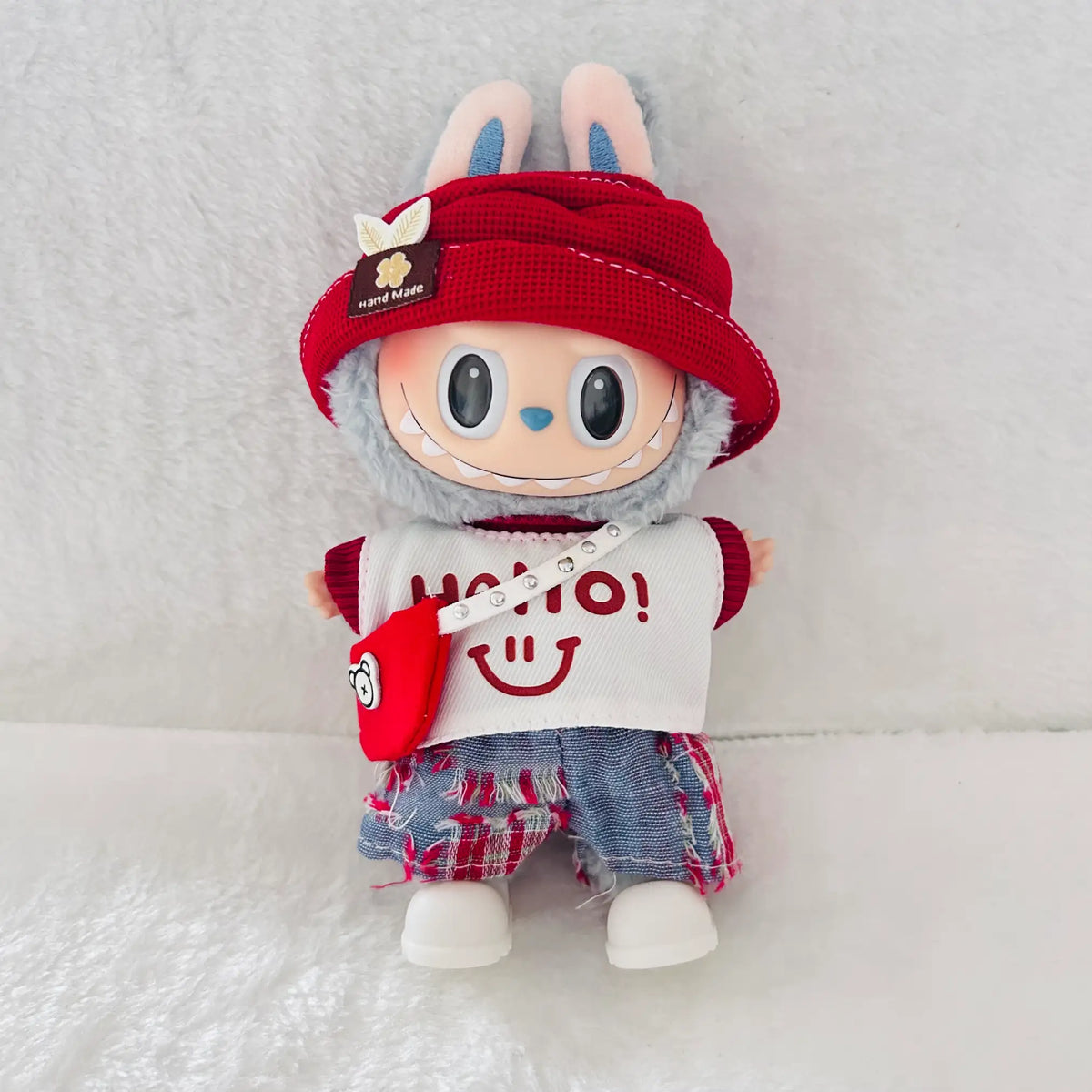 A front view Labubu wearing a clothing set of red bucket hat, smiley graphic tee, plaid shorts