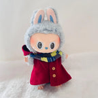 A Labubu doll wearing a bright red hooded coat with buttons and a blue, yellow, and white striped scarf.