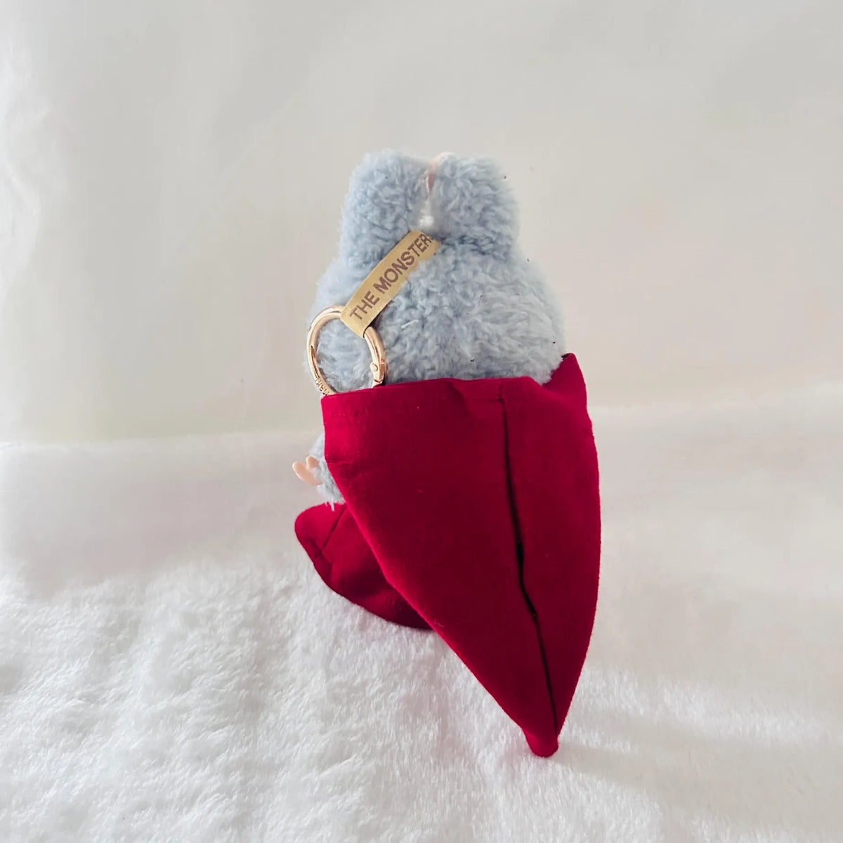 A plush monster toy wearing a red pointed hat cape.