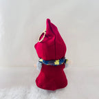 Back view of a Labubu wearing a bright red pointed hat cape, with a blue and yellow patterned scarf.