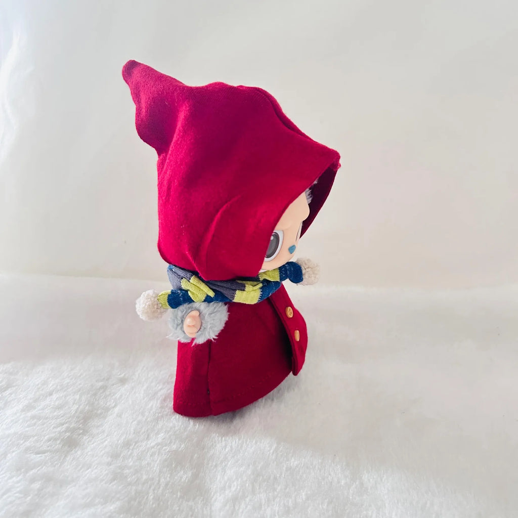 A Labubu plush doll wearing a bright red hooded coat and a blue-and-yellow patterned scarf.