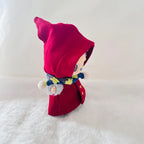 A Labubu plush doll wearing a bright red hooded coat and a blue-and-yellow patterned scarf.