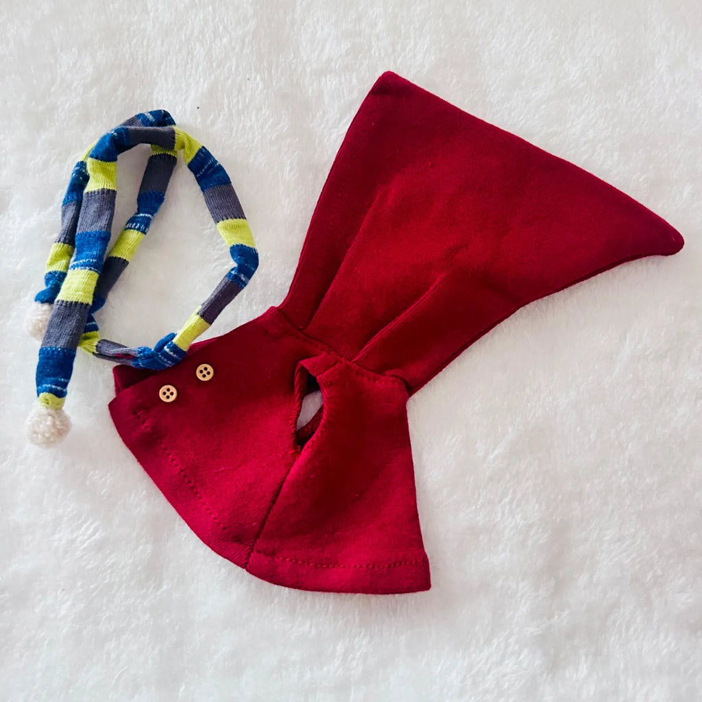 A little red cape with a matching blue, grey, and lime green striped knit scarf accessory.