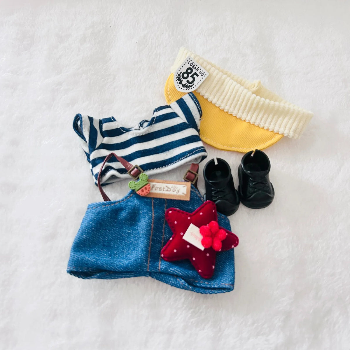 A doll outfit set including a blue-and-white striped top, denim-style shorts, a yellow headband, black shoes, and a red star-shaped hair accessory.